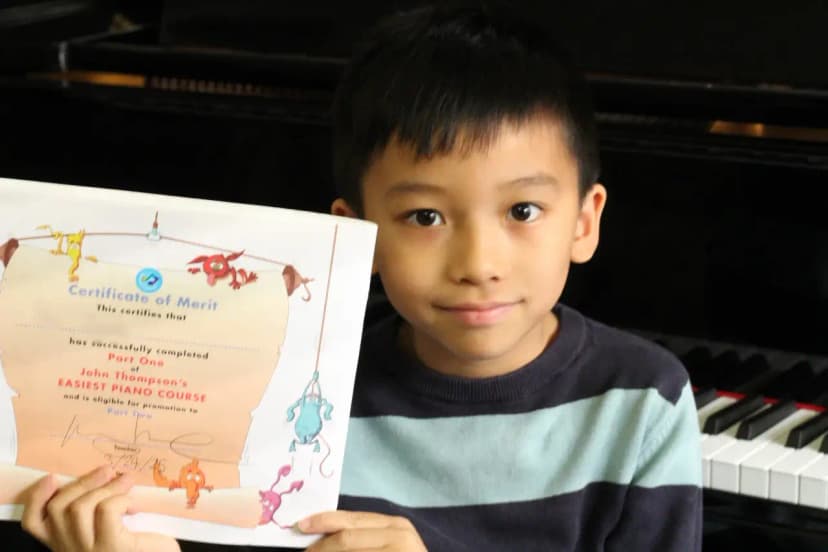 Child student holding their John Thompson Book 1 piano certificate